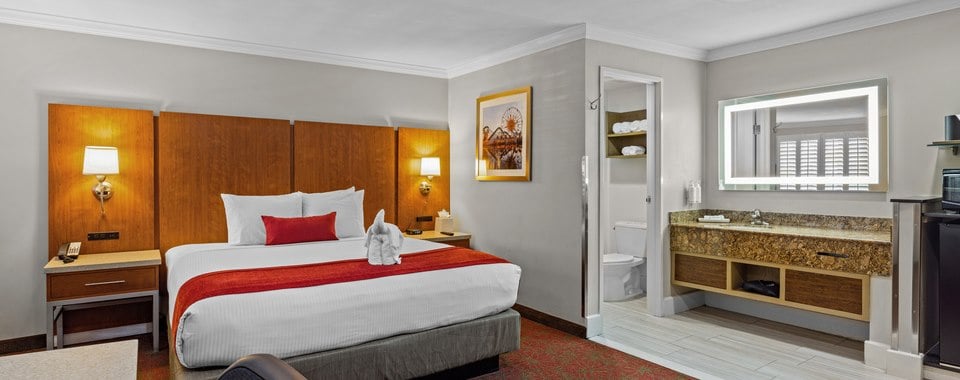 A hotel room with a large bed, nightstands, and a bathroom with a sink and toilet.